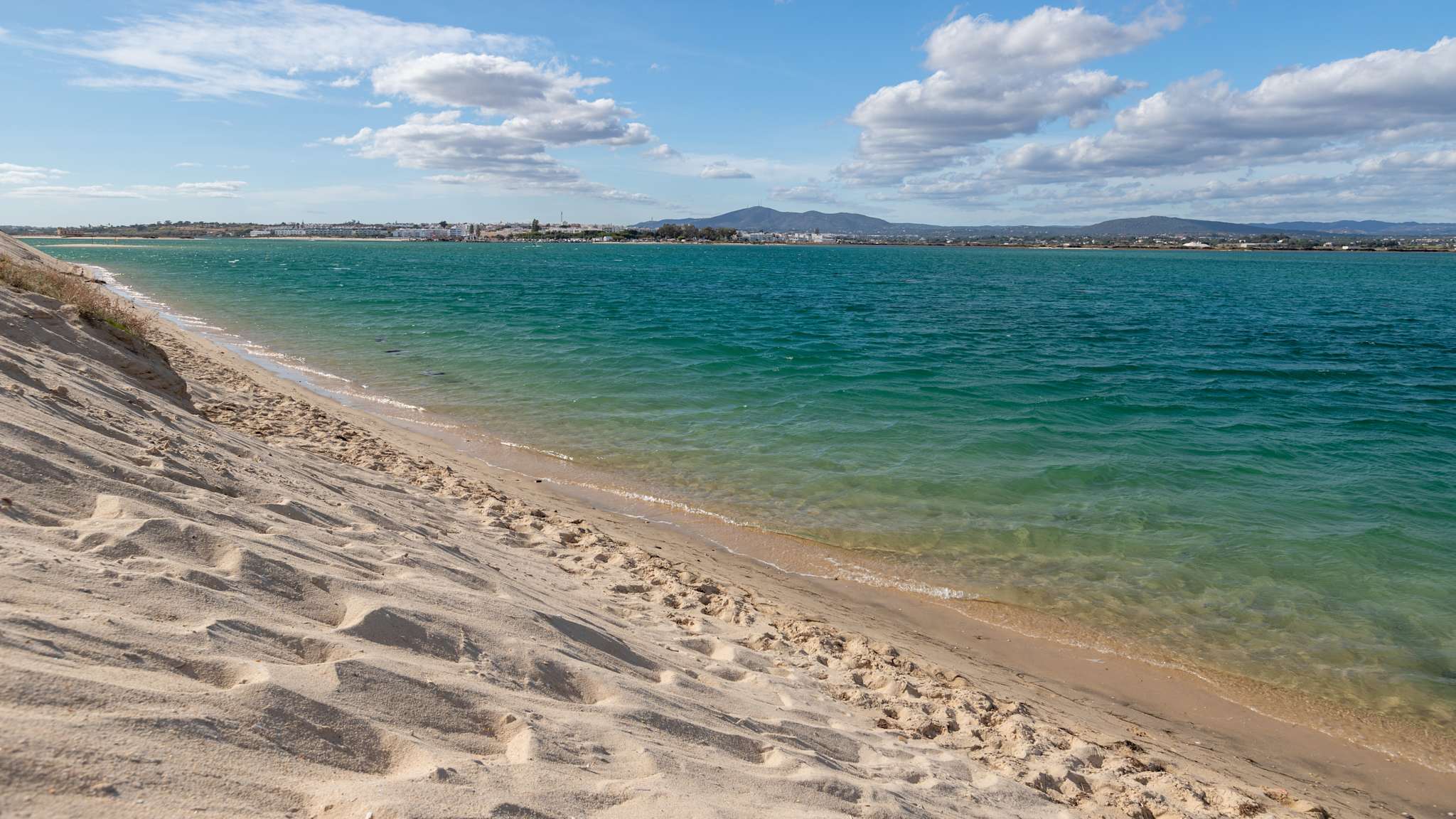Ein Sandstrand mit grünblauem Wasser